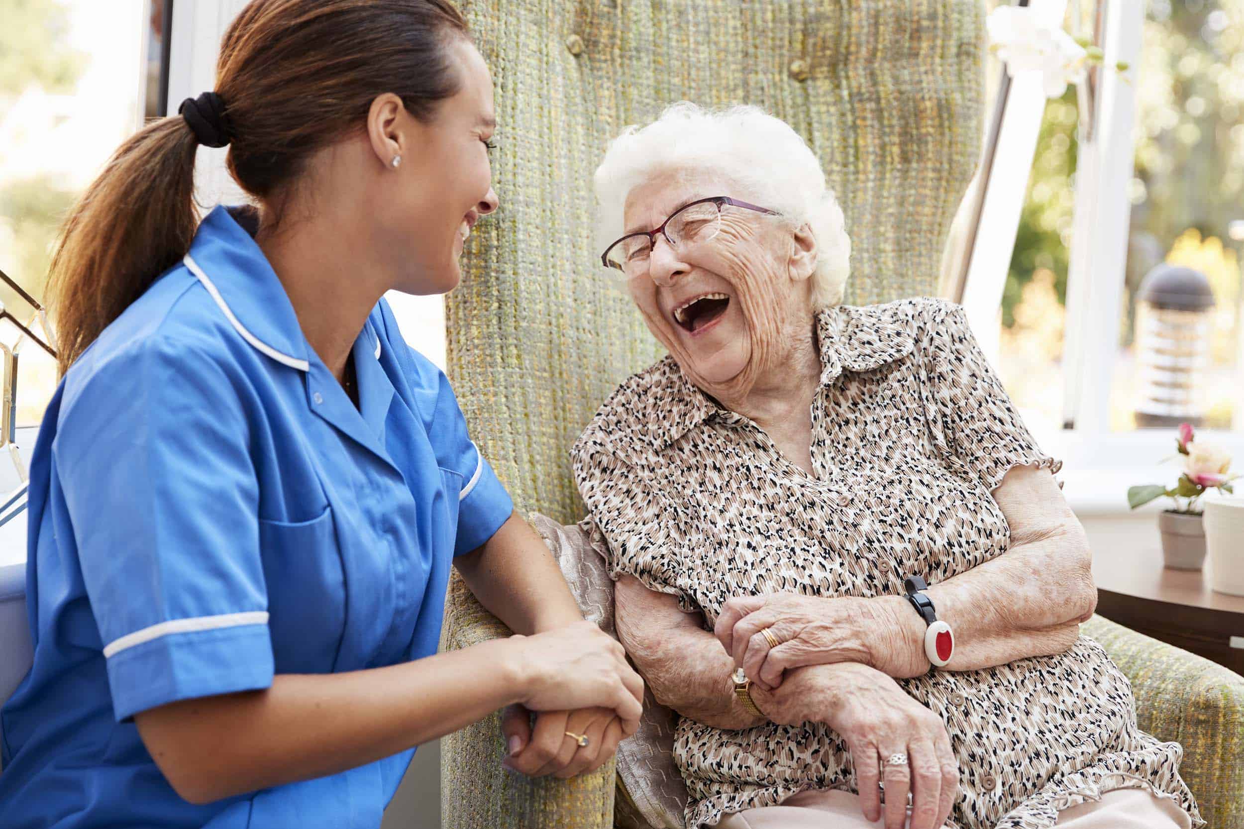 Senior Woman Sitting and Laughing with Nurse