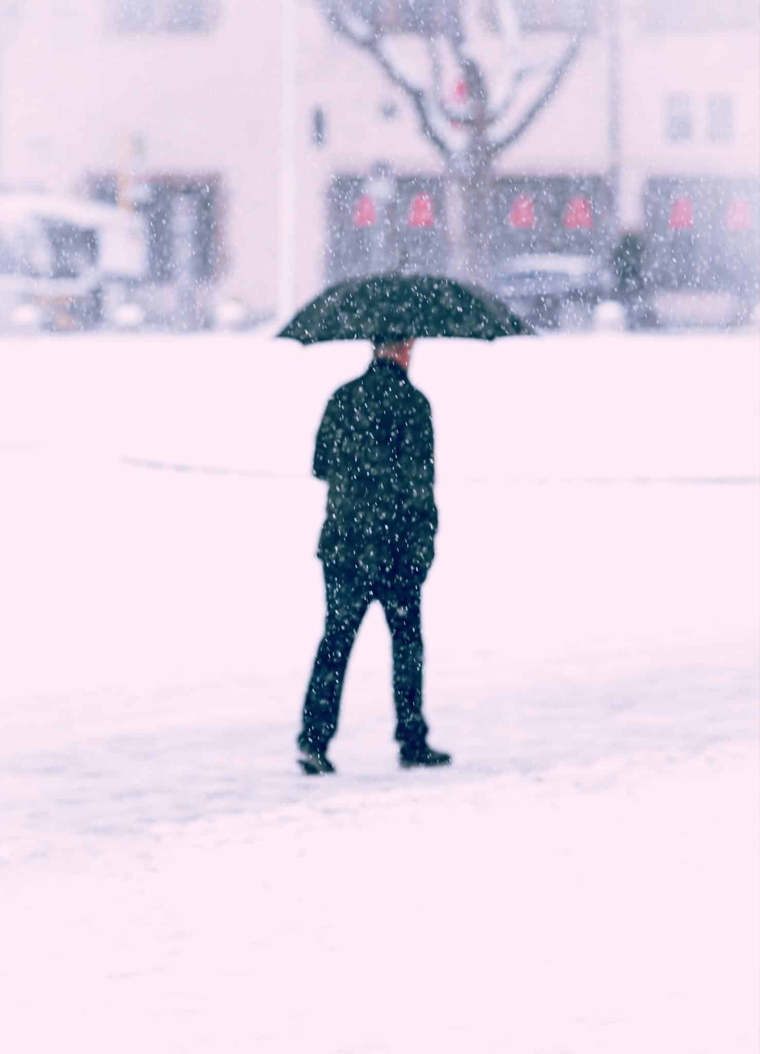 Man walking with umbrella in the snow.
